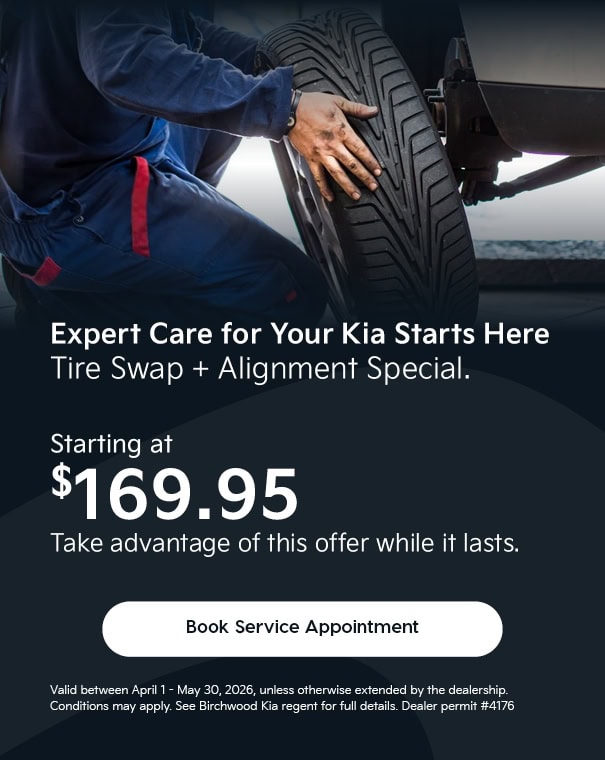 Mechanic installing tire on vehicle, “Expert Care for Your Kia Starts Here” tire swap and alignment special starting at $169.95, auto service promotion with “Book Service Appointment” call-to-action.